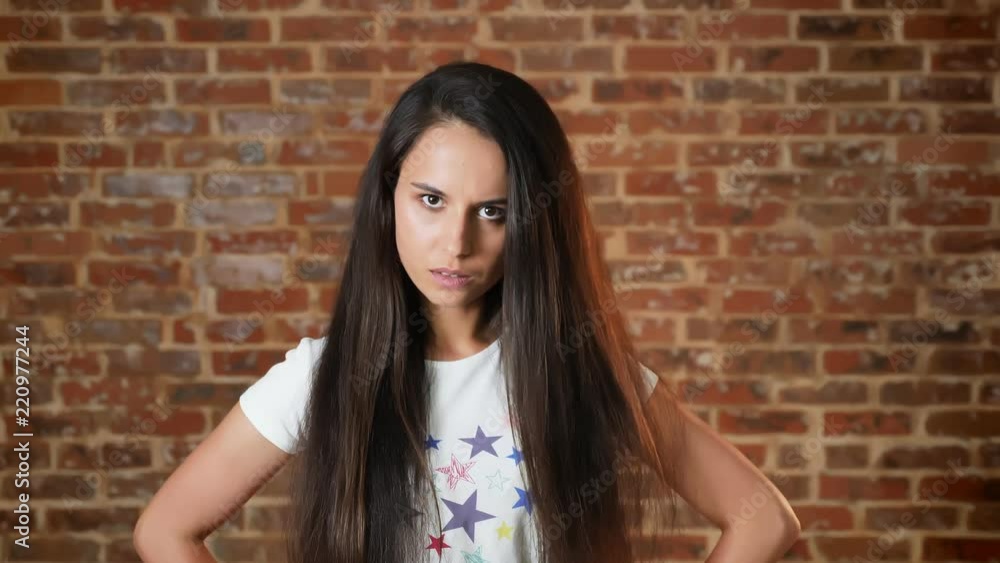 Young girl looking at the camera, haughty, brick wall in the background, portrait Young girl looking at the camera, haughty, brick wall in the background, portrait