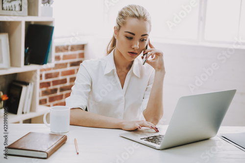Young Smiling Woman Talking on Phone at Desk photo