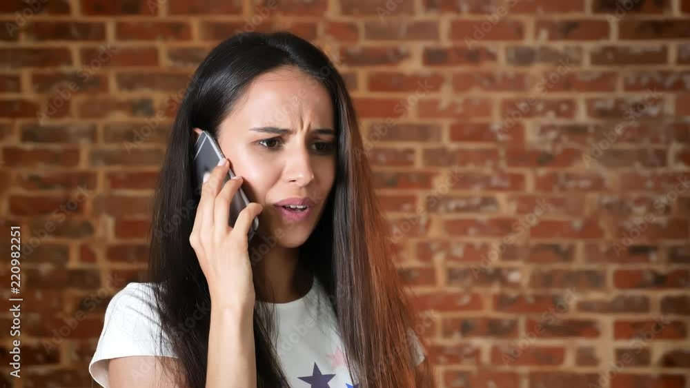 Young cute girl talking on a smartphone, dialogue, brick wall in the background, portrait Young cute girl talking on a smartphone, dialogue, brick wall in the background, portrait