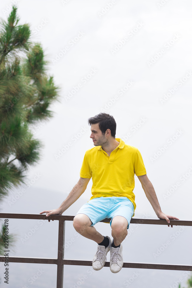 Man looking at camera and sitting on a fence
