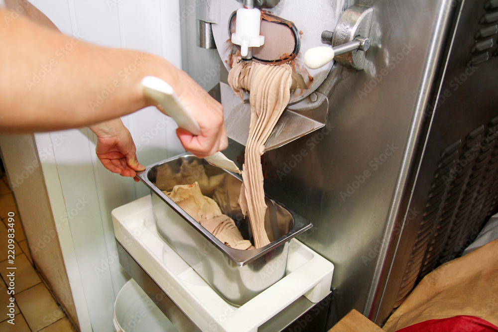 Confectioner in chef uniform is working on ice cream maker machine