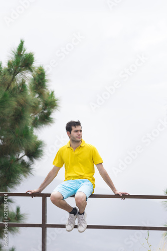 Man looking at camera and sitting on a fence