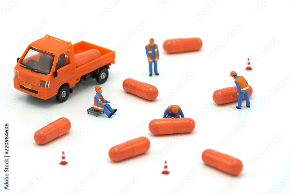 Miniature people Construction worker Load up the car model orange capsule medicine. on white background using as background business concept and Health concept with copy space. Miniature people Construction worker Load up the car model orange capsule medicine. on white background using as background business concept and Health concept with copy space.