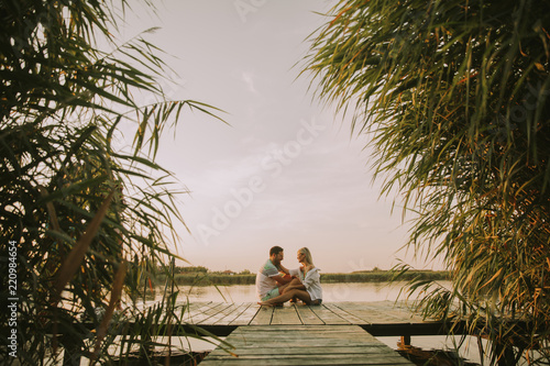 Romantic couple sitting on the wooden pier on the lake