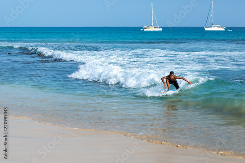 Boy surfing in blue ocean
