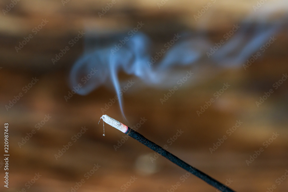 Räucherstäbchen glüht vor hölzernem Hintergrund