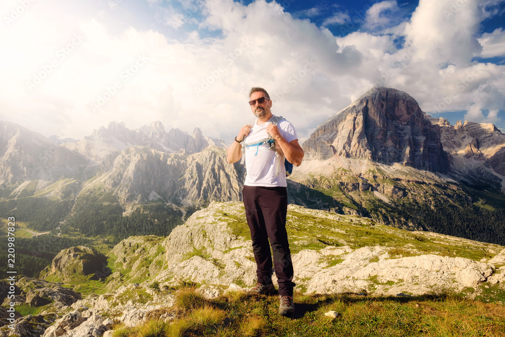 Nestled in the beautiful alpine scenery, a man admires the high-altitude landscape with mountain peaks and cloudy skies.