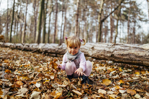 Beautiful and happy little girl enjoying in autumn park.