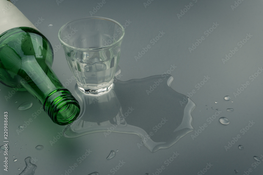 a soju bottle with glass on the wet table. Soju is the colorless