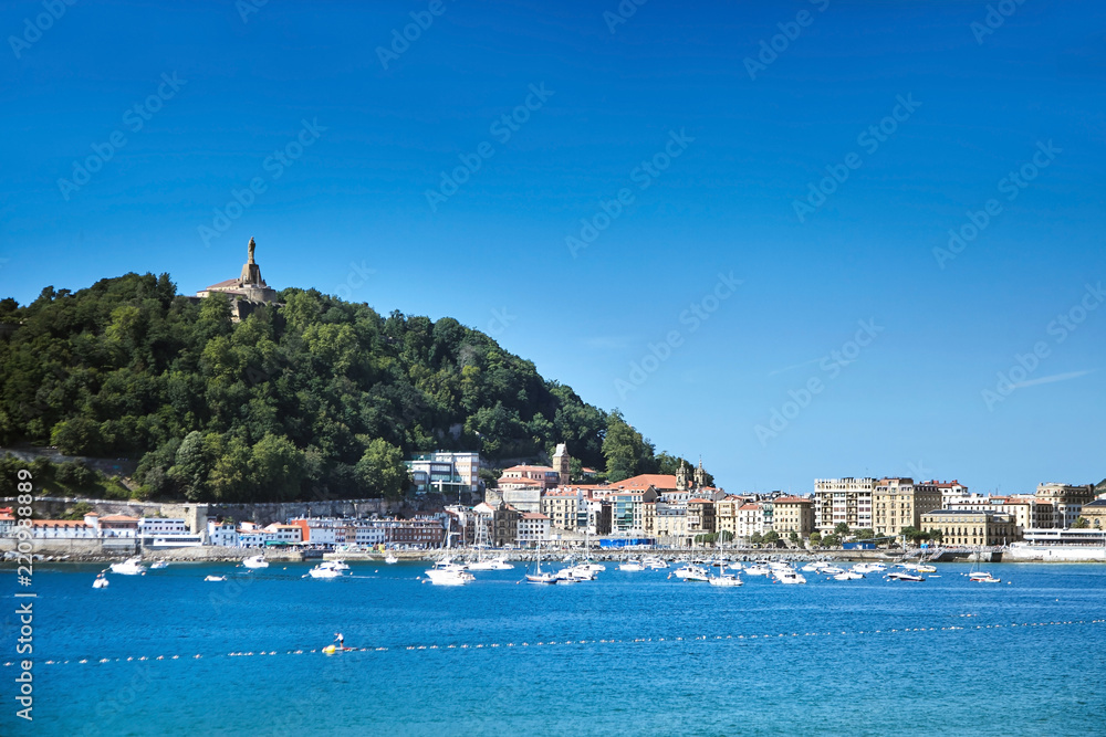 Sea harbor in San Sebastian or Donostia, Basque country, Spain. View of Jesus Christ statue on top of the Urgull mountain and old town