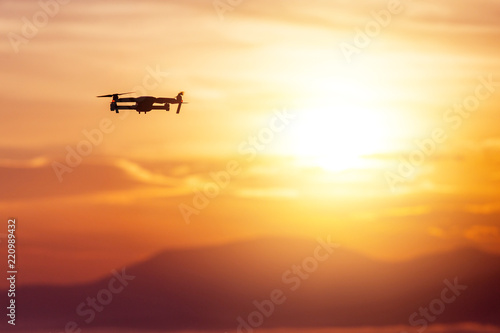 The drone with cinema camera flying over the misty mountains at sunset
