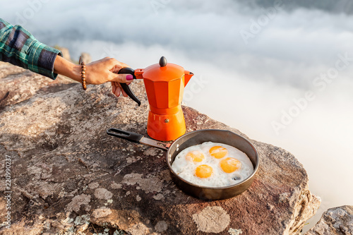 breakfast meal Fried eggs in pan and coffee geyser maker outdoors in mountains, camping food concept