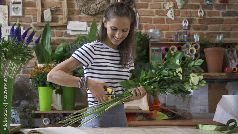 Cheerful young florist cutting stems of flowers in bouquet Cheerful young florist cutting stems of flowers in bouquet