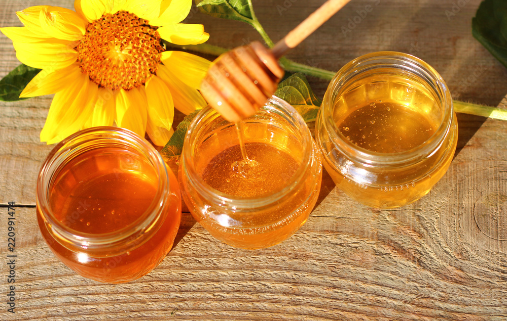 Honey in a glass jar with flowers on the wooden floor. Honey in a glass jar with flowers on the wooden floor.