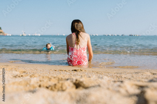 petite fille assise sur le sable au bord de la plage
