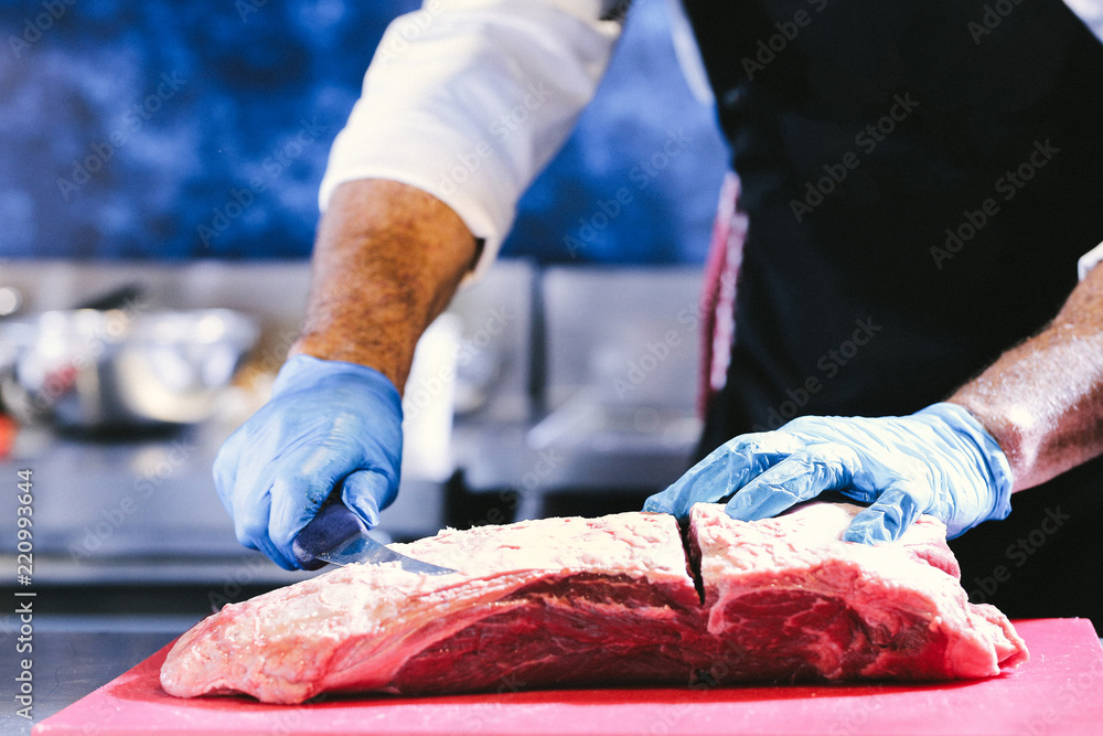 Butcher cutting pork meat on kitchen, Chef cutting fresh raw meat on board, Close up of butcher cutting meat