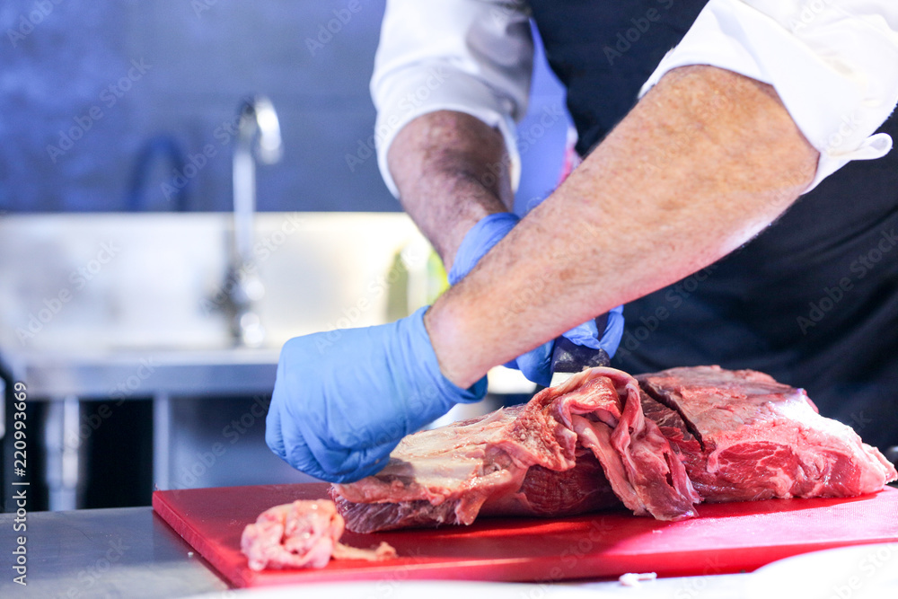 Butcher cutting pork meat on kitchen, Chef cutting fresh raw meat on board, Close up of butcher cutting meat
