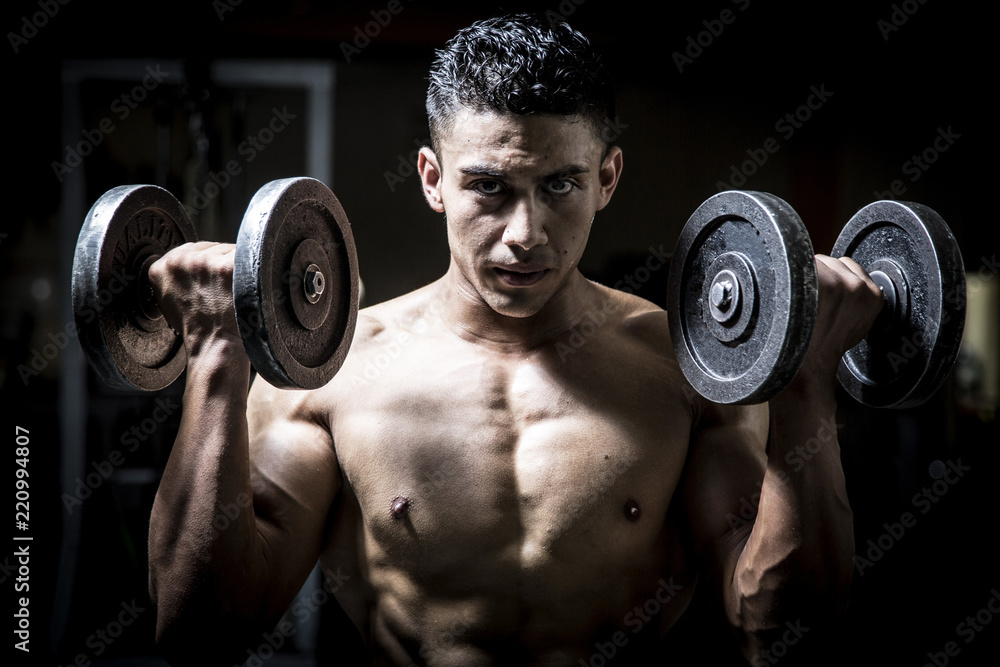 Young man exercising in dark and old gym Young man exercising in dark and old gym