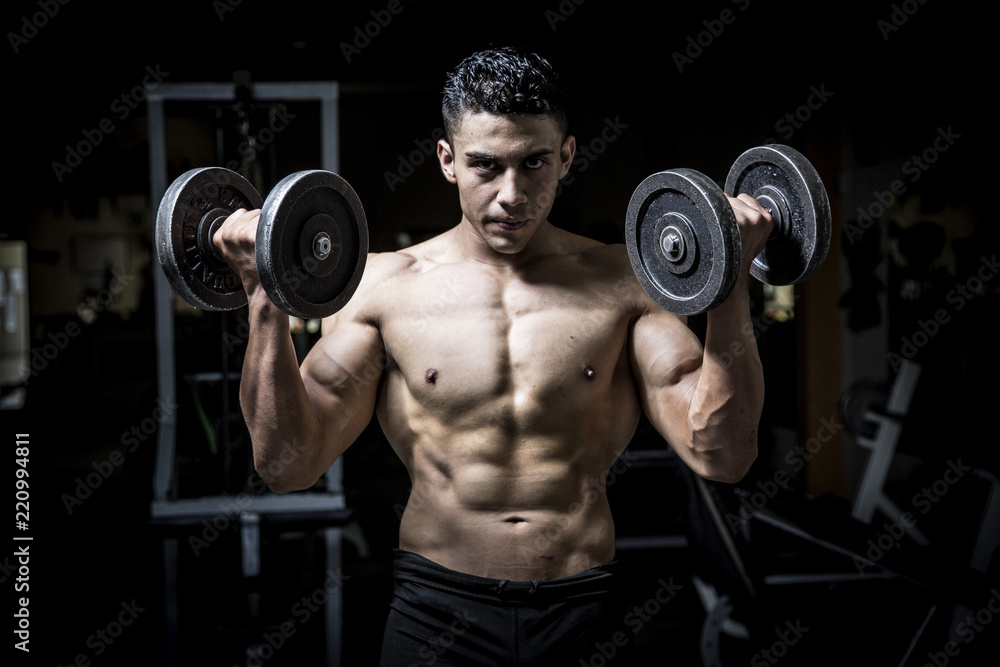 Young man exercising in dark and old gym