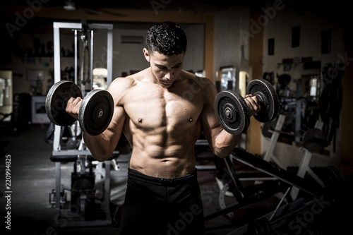 Young man exercising in dark and old gym