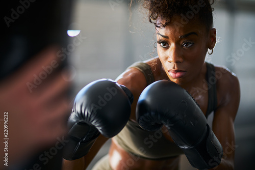 african woman boxing with punching bag in garage gym