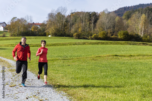 Young couple running on the sunny day in the autumn forest of the Bavarian National Park, Bavaria, Germany