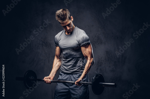 Handsome sportsman with stylish hair dressed in a sportswear doing the exercises with the barbell.