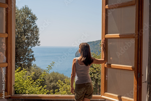 Young woman at a large open window.