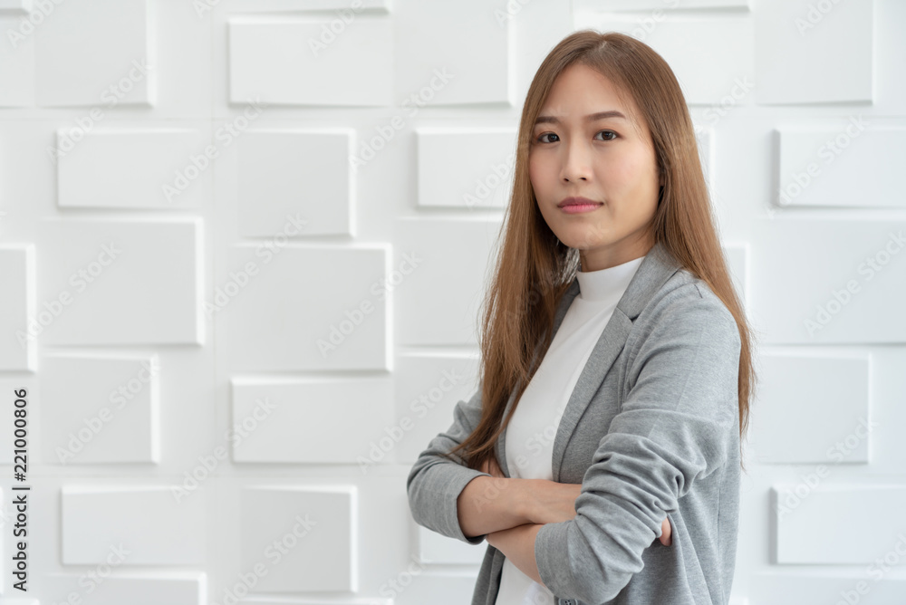 Portrait of a confident Asian business woman standing over white wall. Portrait of a confident Asian business woman standing over white wall.
