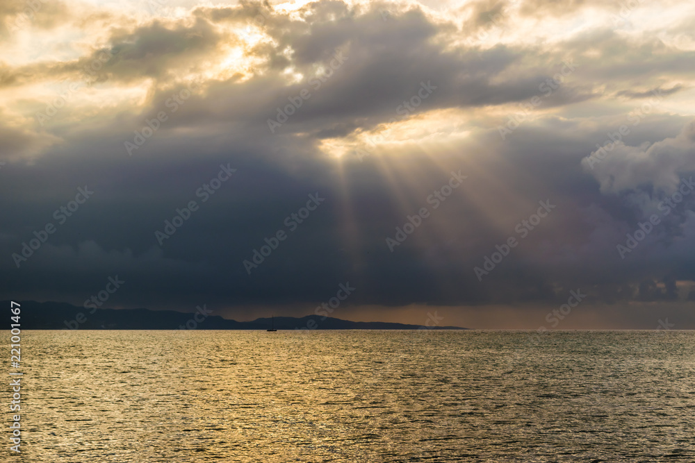Scenic view of sun rays bursting through clouds over the ocean. Concept of breakthrough, hope, signs.