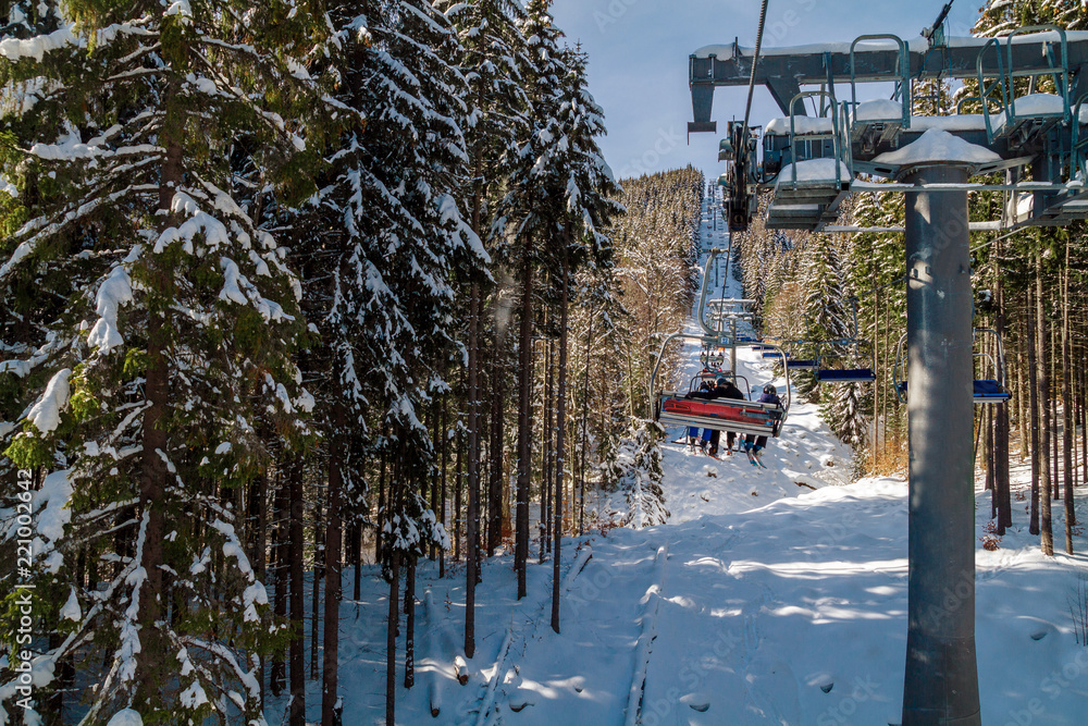 Skiers and snowboarders on a ski lift.view from above on the cable car among the winter forest. Skiers and snowboarders on a ski lift.view from above on the cable car among the winter forest.