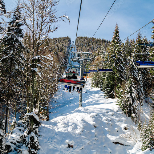 Skiers and snowboarders on a ski lift.view from above on the cable car among the winter forest.
