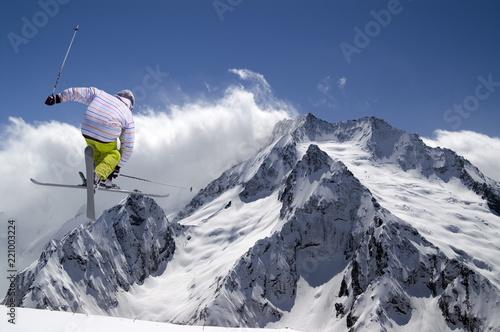 Freestyle ski jumper with crossed skis in high snowy mountains photo
