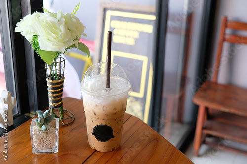 Iced cappuccino on wooden table, white rose photo