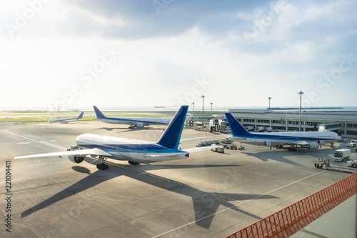 Busy airport with many airplanes and Preparation of the airplane before flight at sunset, view through window