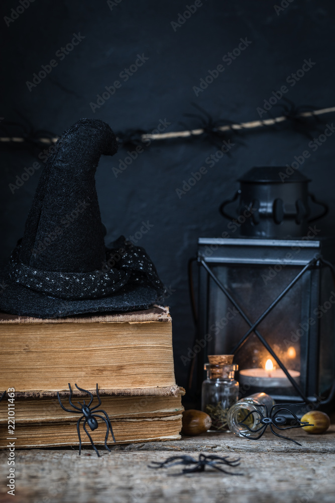 Halloween holiday background with lantern, spiders, old books, black witchhat