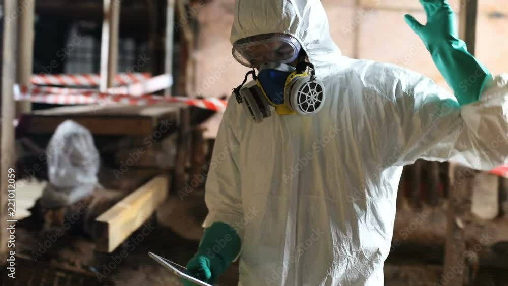 Two men wearing yellow and white hazmat suits coming abandoned building after accident. One guy opening briefcase, colleague holding digital tablet in hands Two men wearing yellow and white hazmat suits coming abandoned building after accident. One guy opening briefcase, colleague holding digital tablet in hands