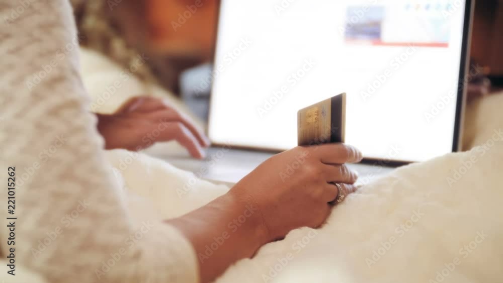 Closeup 4k video of young woman using laptop and holding credit card in hand. Concept of online shopping and purchases in internet Closeup 4k video of young woman using laptop and holding credit card in hand. Concept of online shopping and purchases in internet