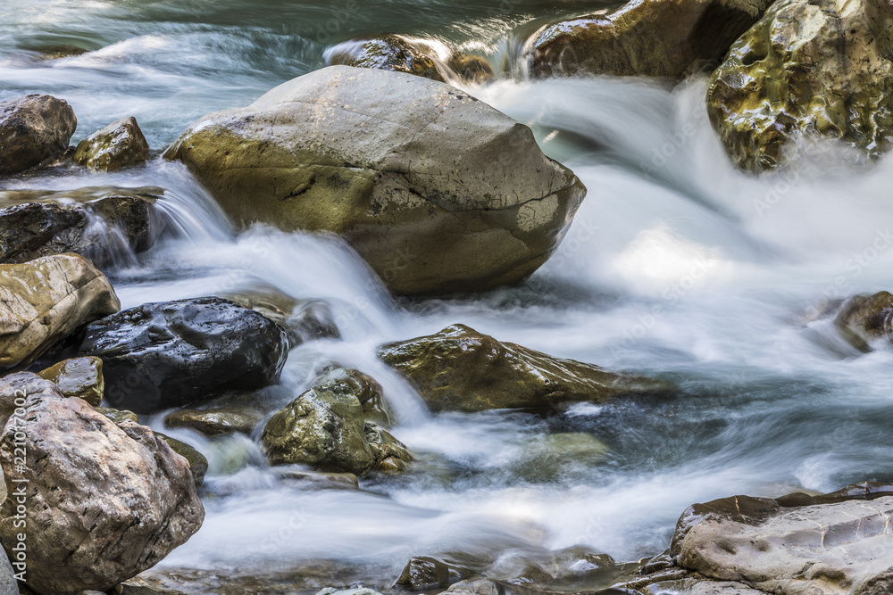 A long exposure of a river flowing along rocks A long exposure of a river flowing along rocks