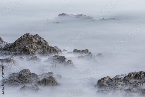 A long exposure image of rocks in the ocean