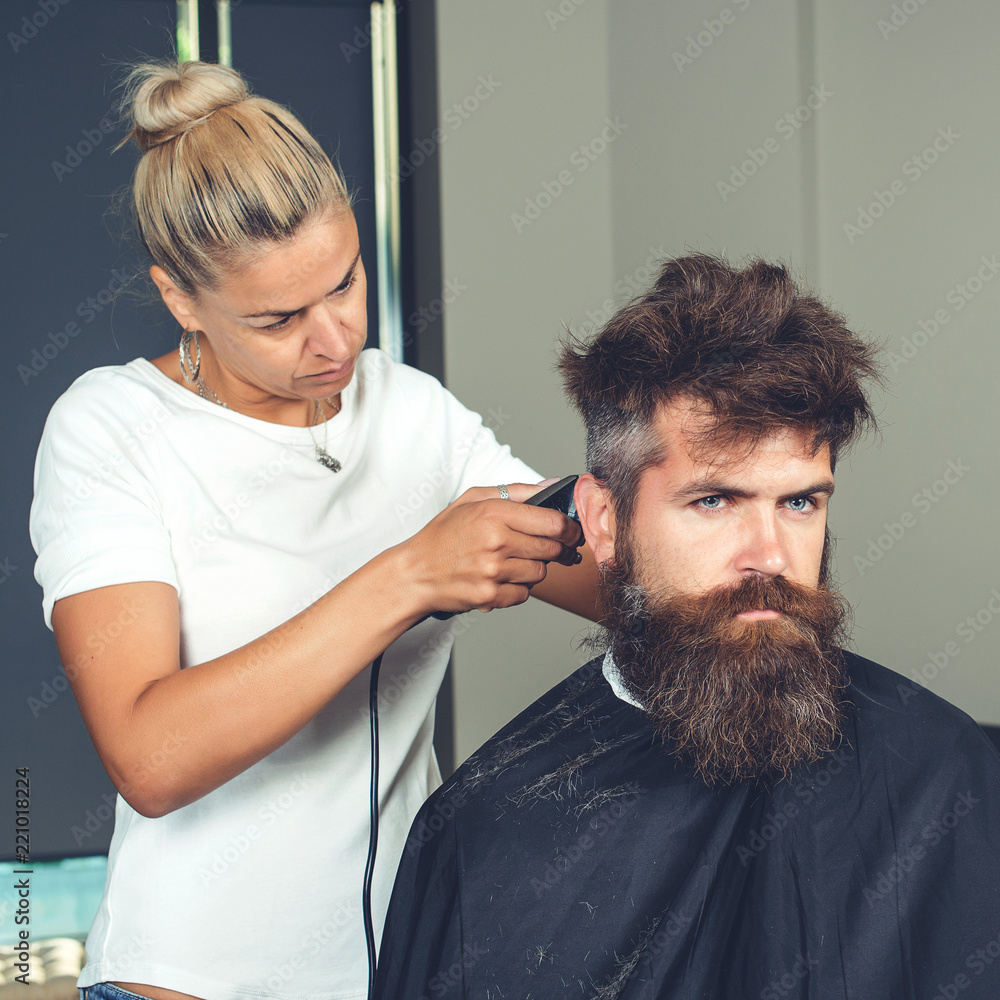 Master cuts hair and beard of men, beauteous woman hairdresser makes  hairstyle for man with beard. Hipster brutal bearded male. Female  hairdresser cutting hair of smiling man client at beauty salon Stock