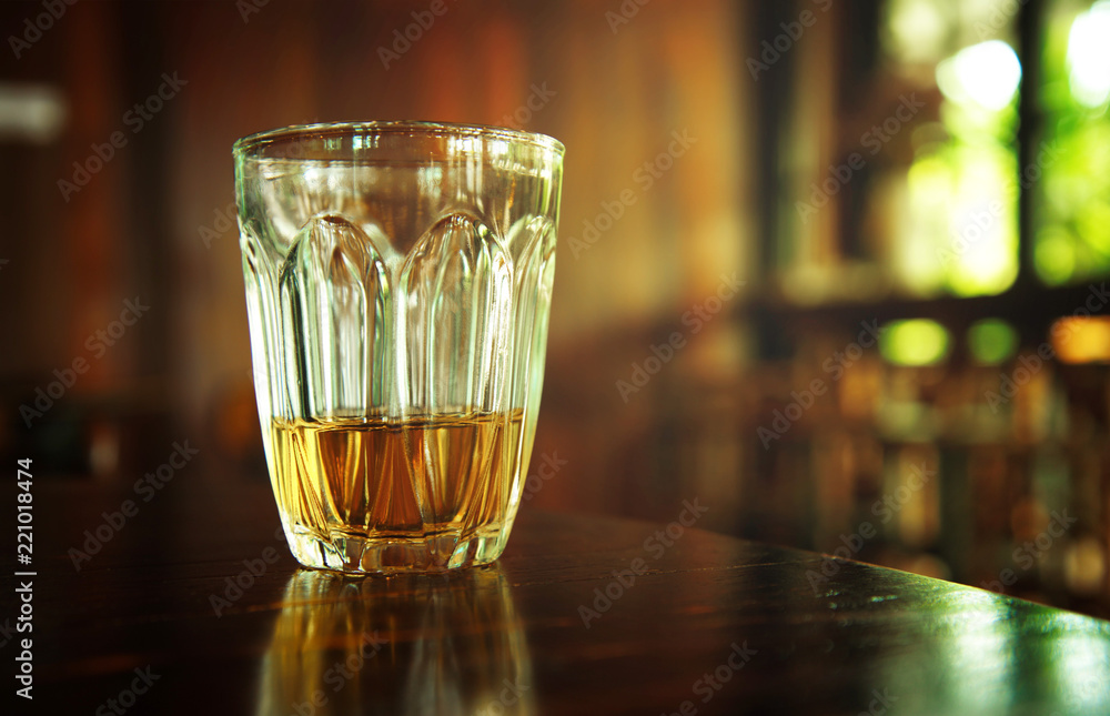 yellow whiskey alcohol drinking on wood table in warm cozy night pub or bar background