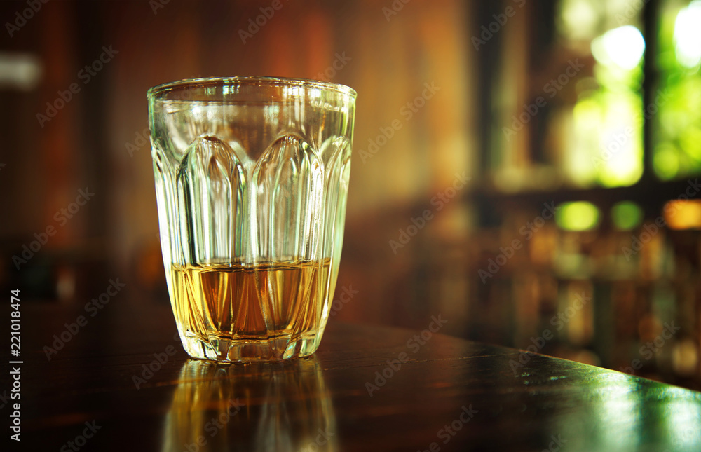 yellow whiskey alcohol drinking on wood table in warm cozy night pub or bar background yellow whiskey alcohol drinking on wood table in warm cozy night pub or bar background