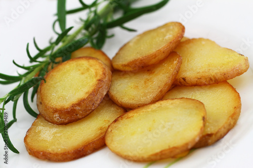 Crunchy fried potato slices with peel with fresh rosemary, closeup 