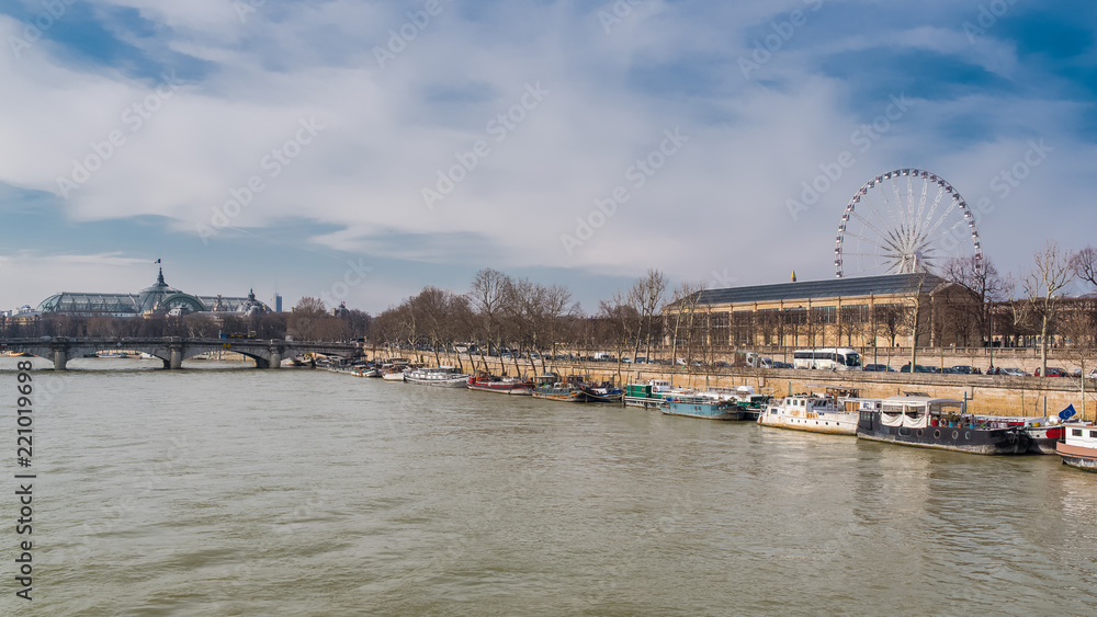 Paris, panorama of the Concorde bridge, the Grand-Palais in background, the big wheel and houseboats on the Seine 
