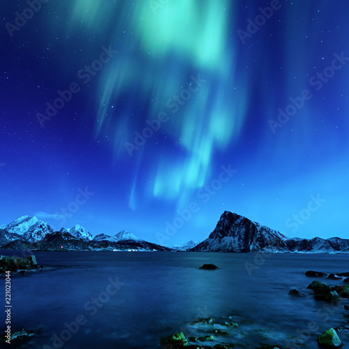 Fototapeta Naklejka Na Ścianę i Meble -  Northern Lights, Aurora Borealis shining green in night starry sky at winter Lofoten Islands, Norway