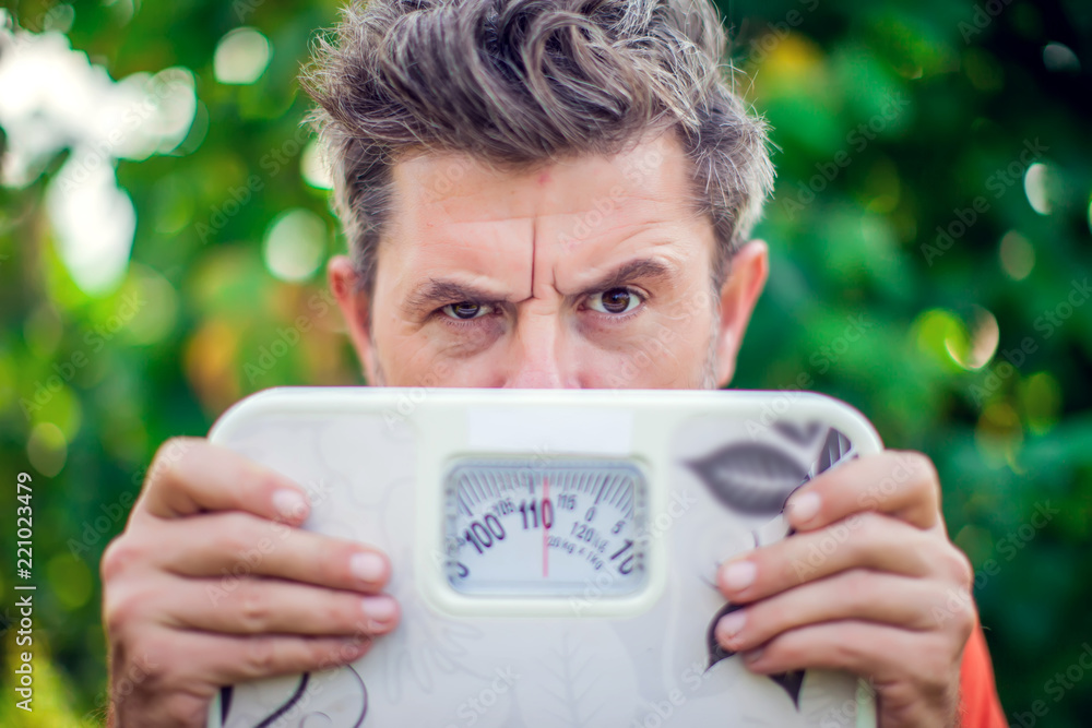 Man holding scales and looking with wondering outdoor Man holding scales and looking with wondering outdoor