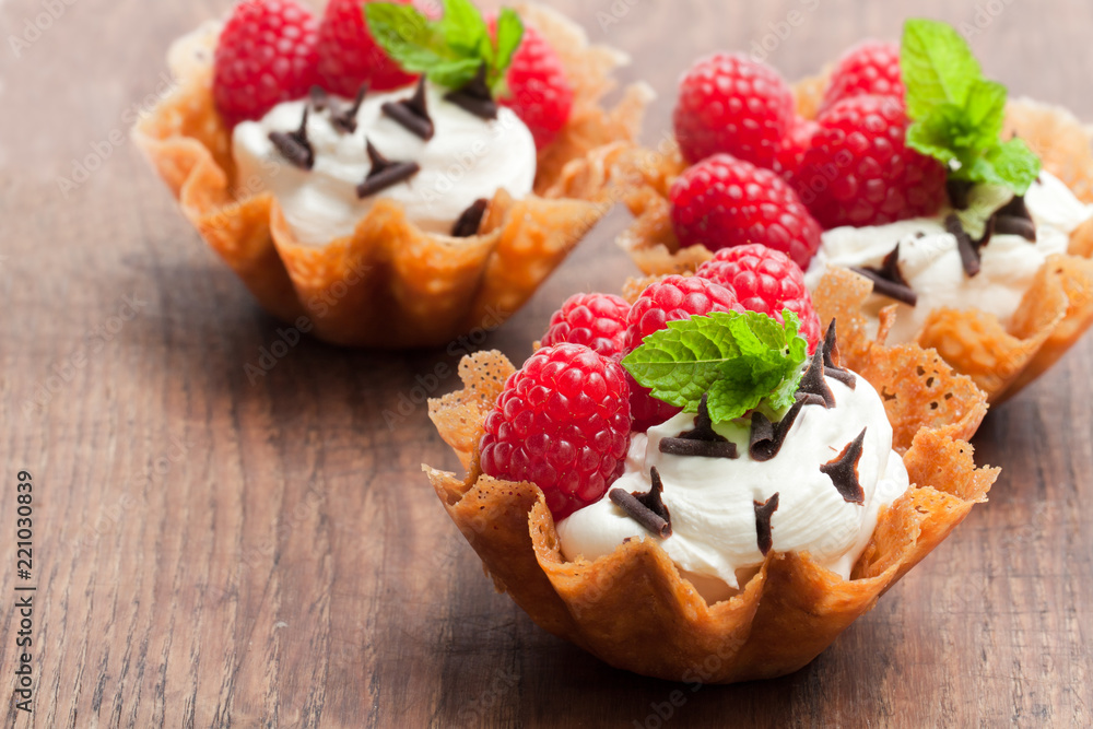Brandy snap baskets with ice cream and berries on wooden table Brandy snap baskets with ice cream and berries on wooden table