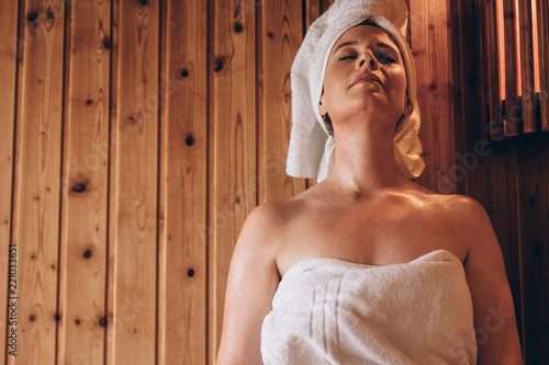 Obraz na plátne Woman sitting in a wooden spa with eyes closed.
