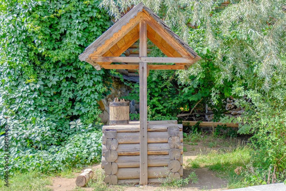 Old wooden well with bucket in rustic style. Old wooden well with bucket in rustic style.